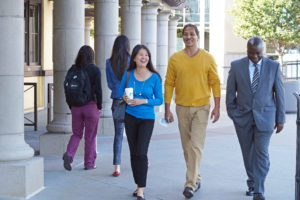 woman in blue shirt and man in yellow shirt walking on campus